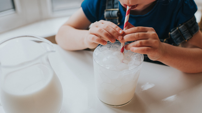 child blowing bubbles into milk