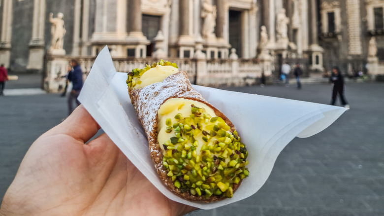 A hand holding a pastry and napkin.