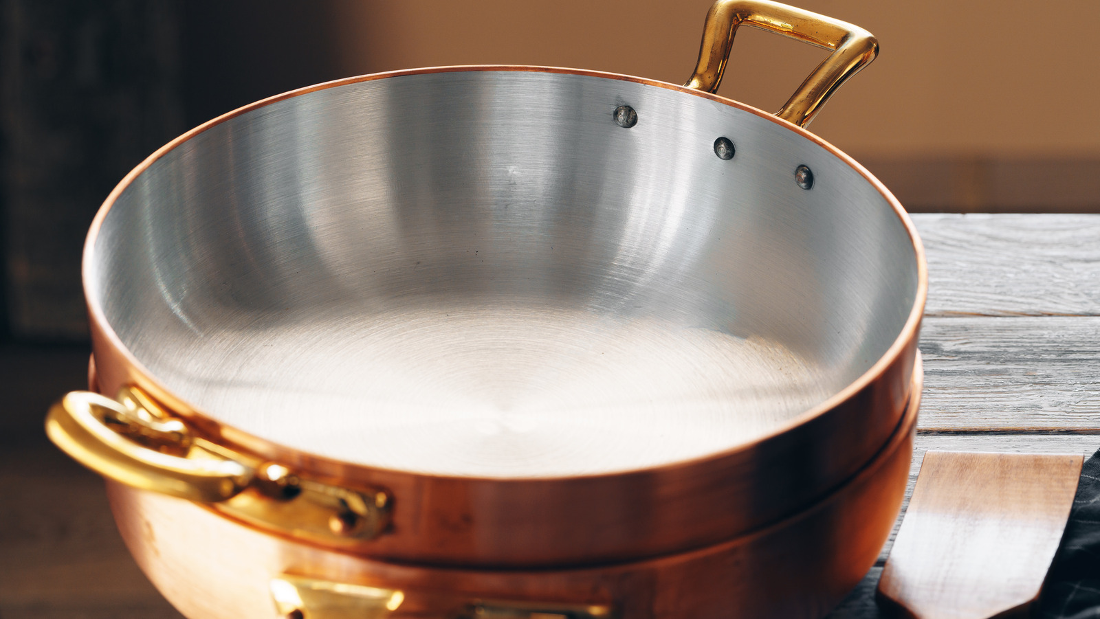 Why must copper pans be lined with a tin coating on the interior?