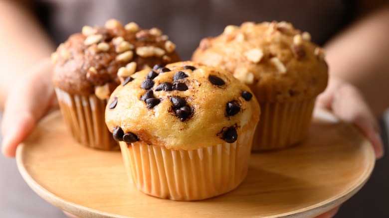 Three different muffins on a wooden tray