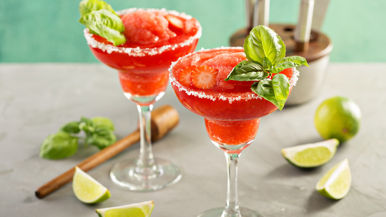 Frozen strawberry cocktail with lime wedges and basil
