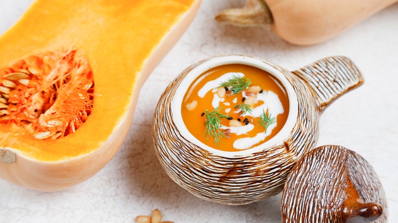 Butternut squash soup in a bowl and raw squash