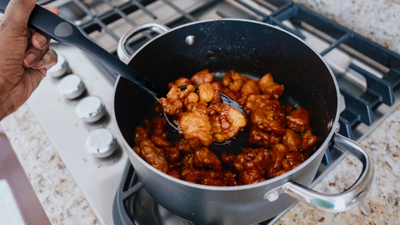 Orange chicken cooking in pot