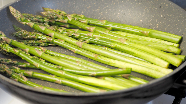 Asparagus in frying pan with lid