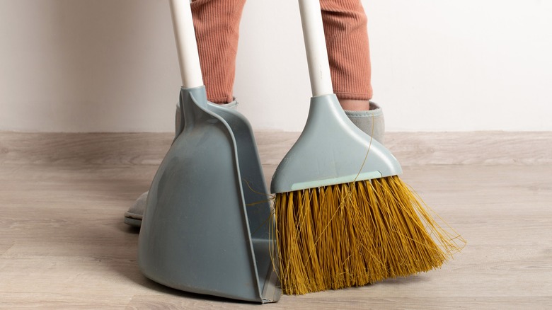 Person uses broom and dustpan