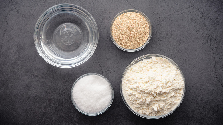 Water, yeast, flour and sugar in bowls