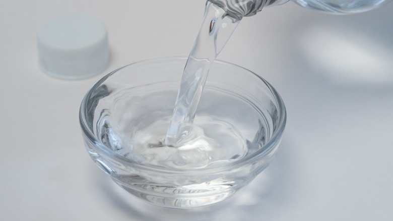 Bottle pouring distilled white vinegar into dish