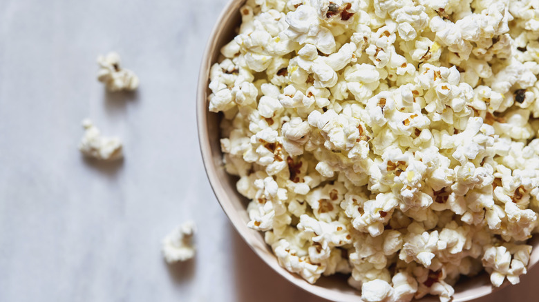 Bowl of popcorn with kernels on counter