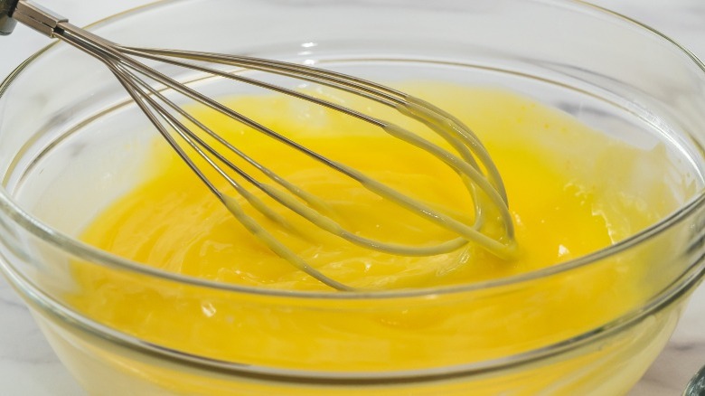 A wire whisk in a bowl of lemon curd