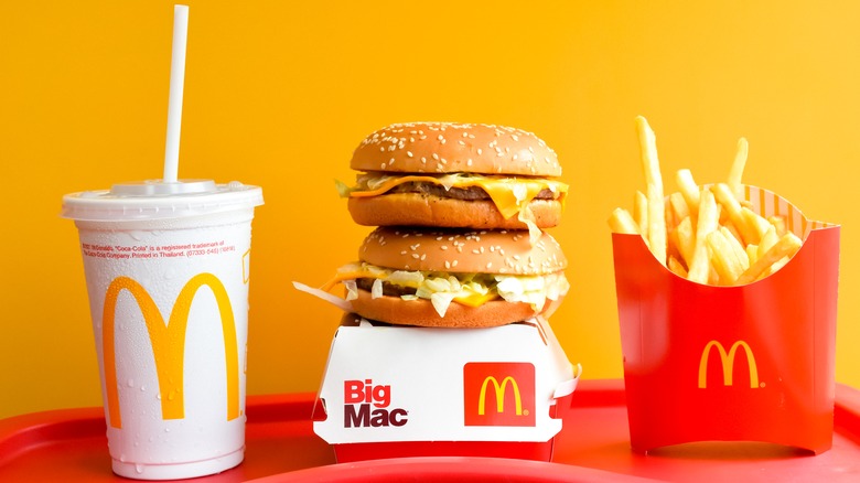 Stack of Mcdonalds burgers with fries and a drink