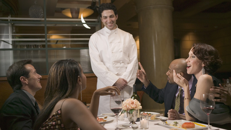 chef at restaurant table with diners