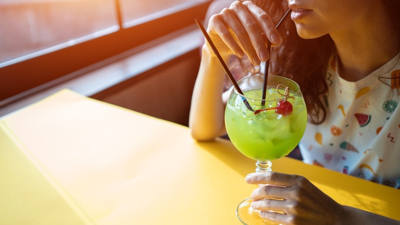 Woman sipping a Midori Sour