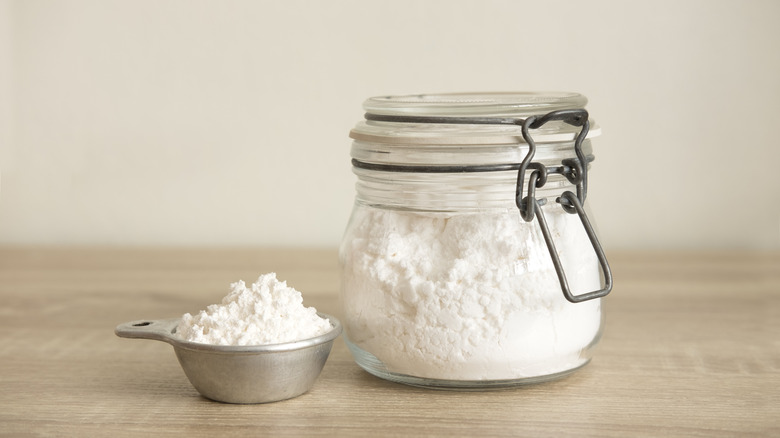 fluffed flour in jar and measuring cup