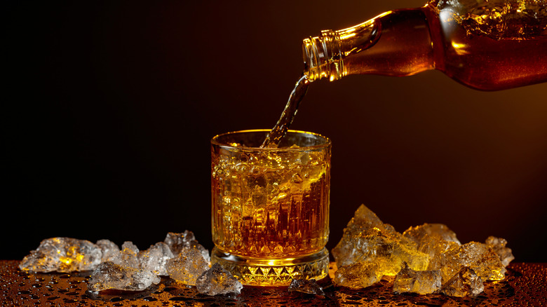 Pouring whiskey into a glass with ice