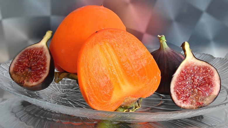 Halved persimmon and figs in a glass dish