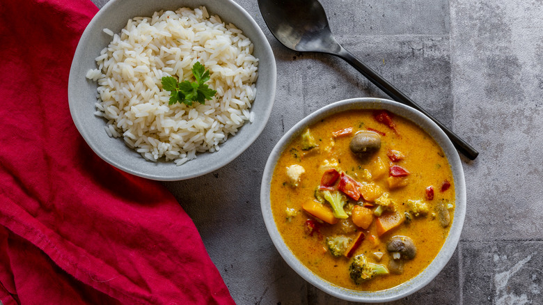 A bowl of pumpkin curry with a bowl of rice