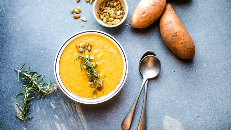 A bowl of sweet potato soup with ingredients nearby