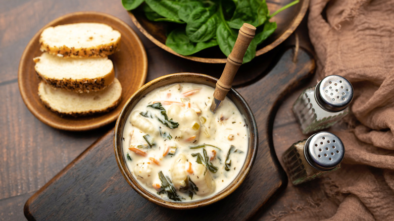 A bowl of creamy gnocchi soup with sliced bread on the side