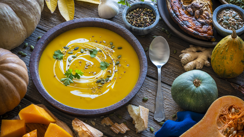 A bowl of soup surrounded by fall vegetables