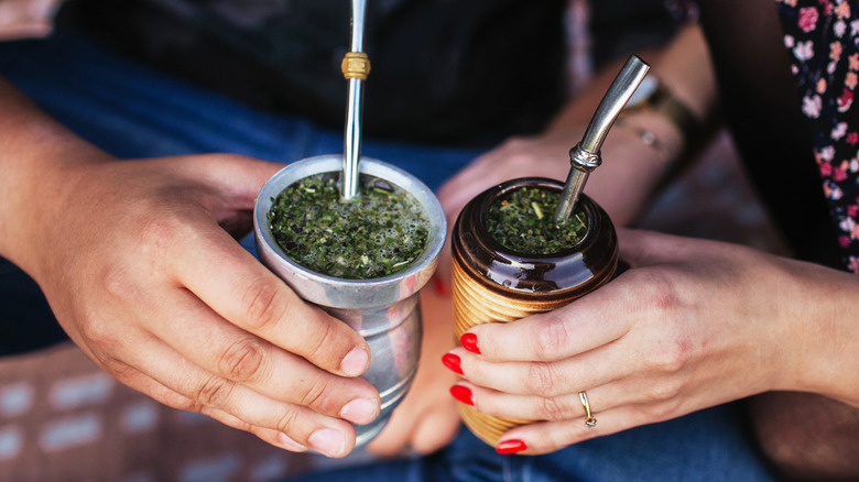 hands holding yerba mate cups