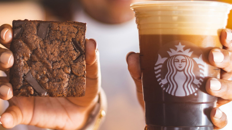 woman holding Starbucks brownie and coffee in hands