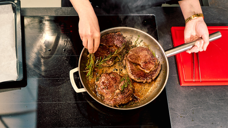 steaks heating on stovetop pan