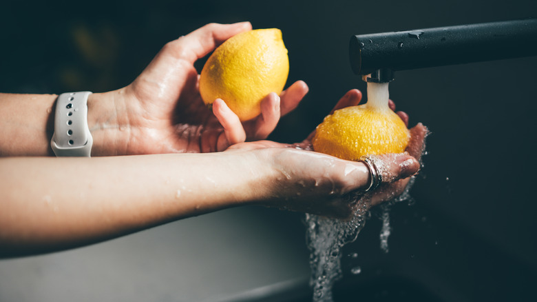 Hands washing lemons in sink