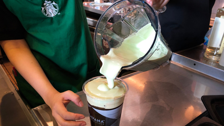 pouring Starbucks matcha cold foam on iced coffee