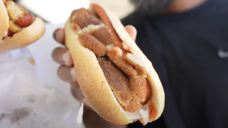 Man holding fish cake hot dog