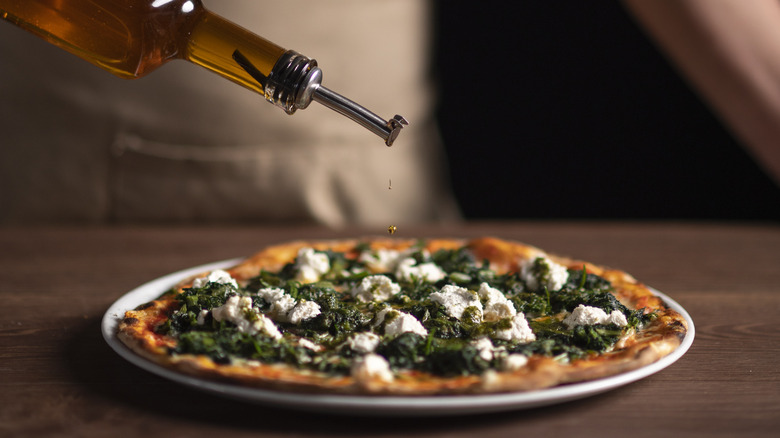 chef pouring oil on pizza