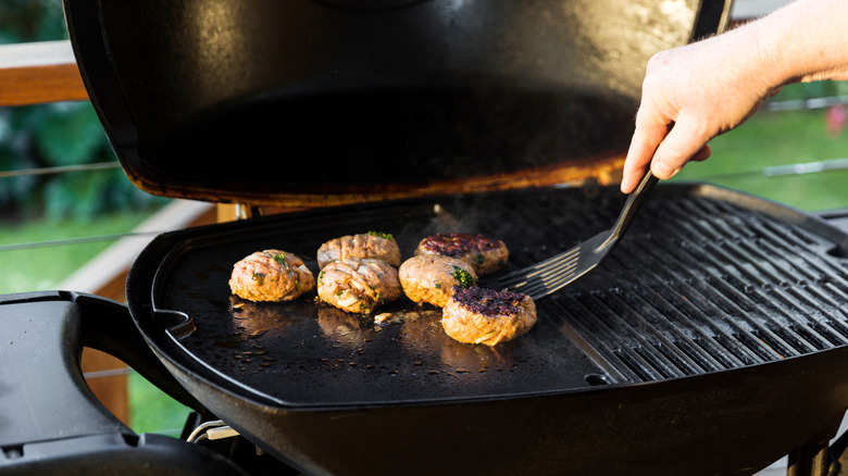 Spatula flipping patties on grill