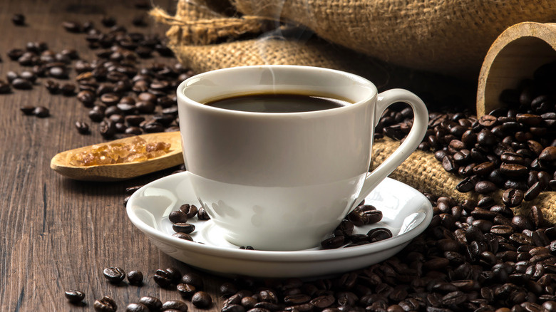 Cup of steaming coffee next to beans