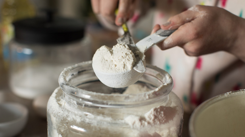 woman levels a scoop of flour