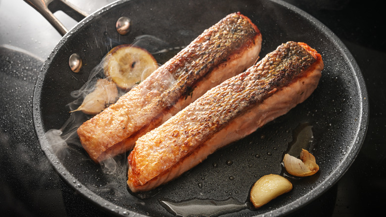 crispy salmon cooking in pan 