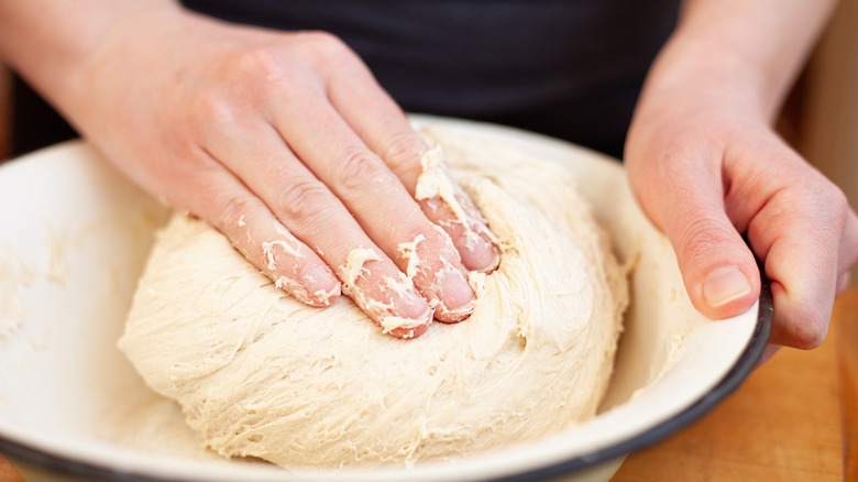 chef kneading dough in bowl