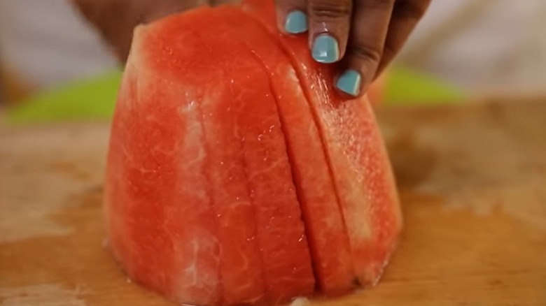 Fingers gripping slices watermelon section