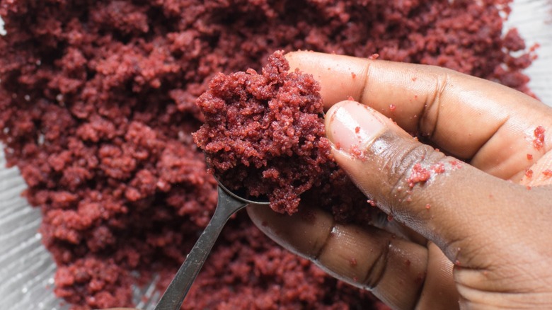 Hand rolling brown cake batter into a ball