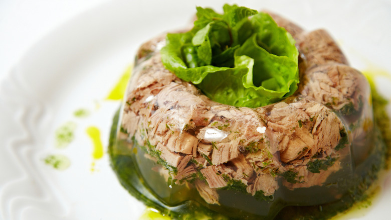 Tuna and green jell-o garnished with a leaf of lettuce on a white platter