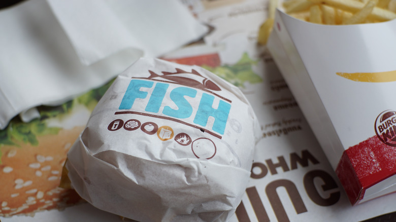 burger king fish sandwich in wrapper with side of fries