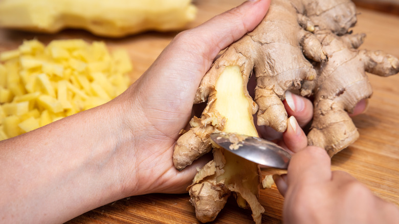 hands peeling ginger with spoon