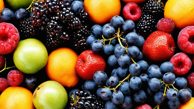 An arrangement of fresh berries, grapes, oranges, and apples