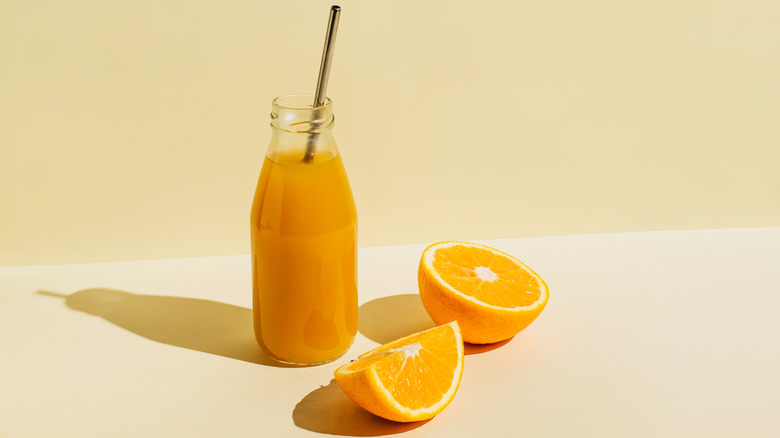 glass of fresh orange juice with orange halves