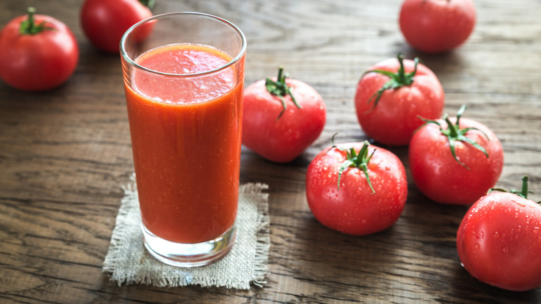 fresh tomato juice in glass with tomatoes nearby