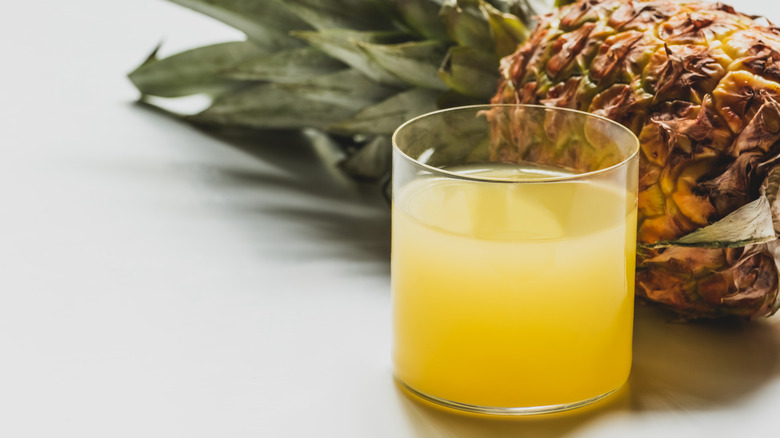 glass of fresh pineapple juice with pineapple laying sideways