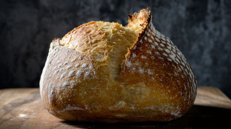 crusty sourdough loaf on board with dark background