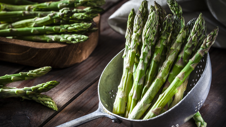 Asparagus on a cutting board and in a colandar