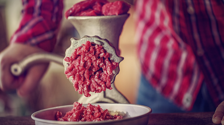 person grinding beef by hand 