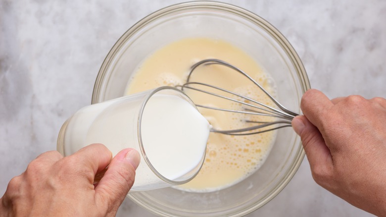 pouring milk or cream into eggs