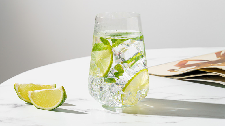 Gin and tonic on table with lime wedges
