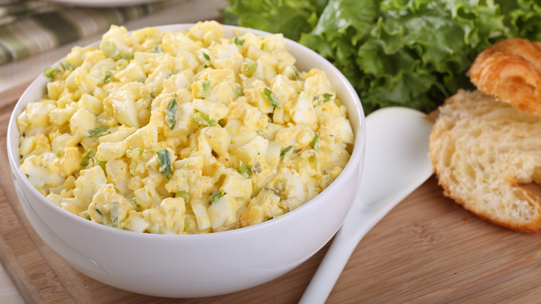 Egg salad in bowl near bread